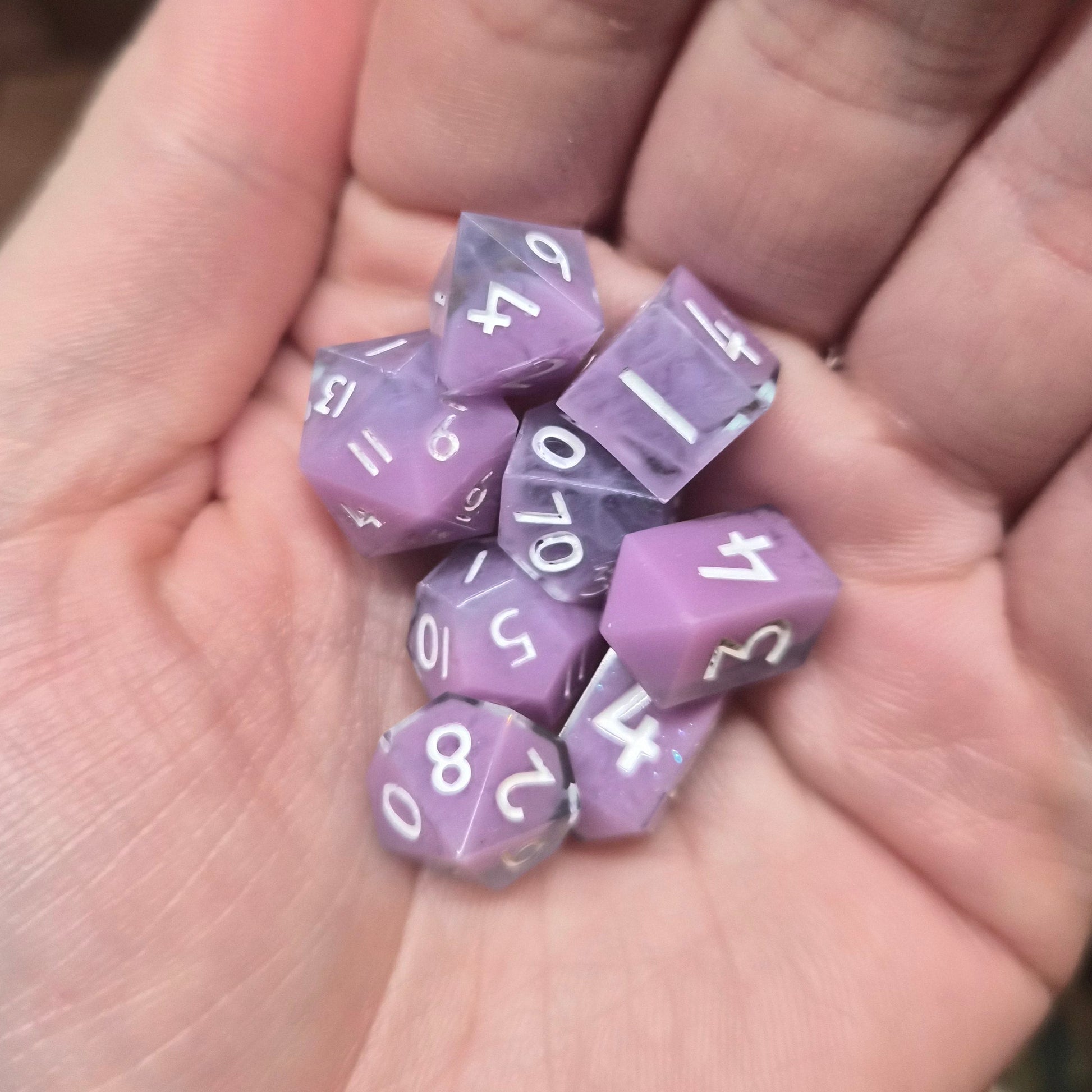 Purple polyhedral dice with white numbers held in a hand