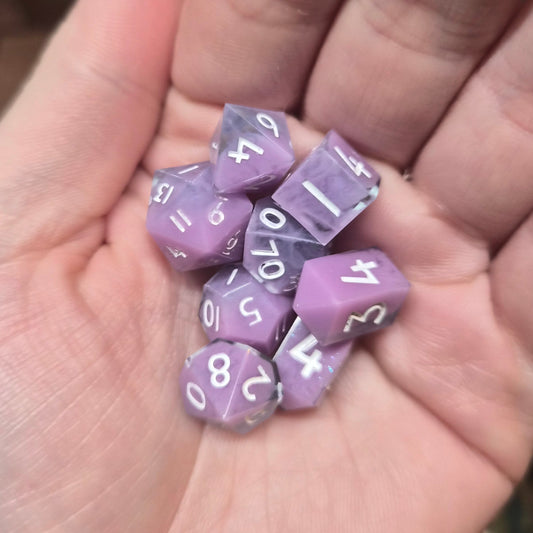 Purple polyhedral dice with white numbers held in a hand
