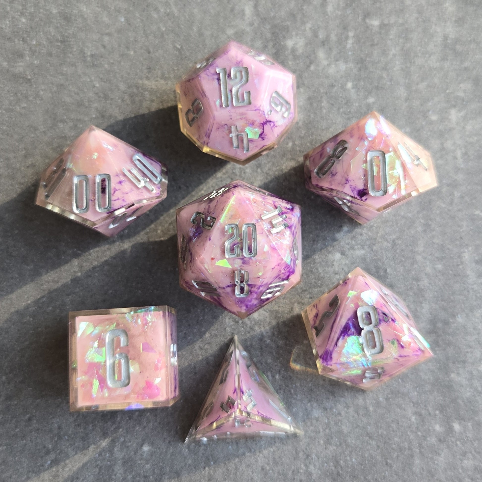 Set of pink and purple polyhedral dice on a gray surface