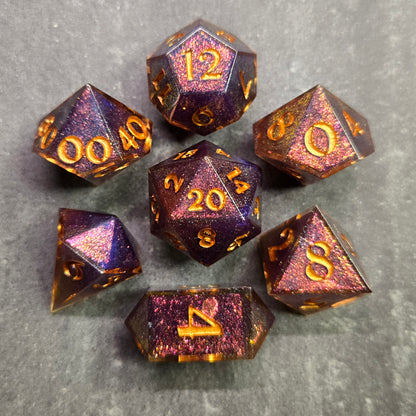 Set of purple and gold polyhedral dice on a gray surface
