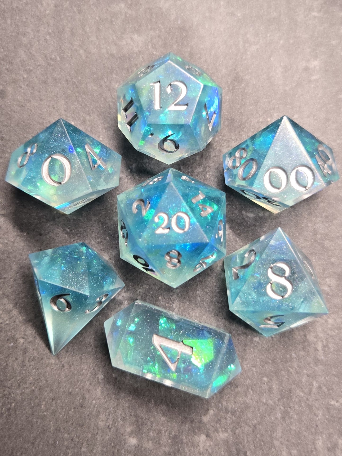 Set of blue iridescent polyhedral dice on a gray background
