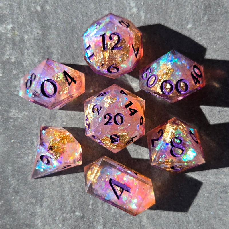 Set of pink and gold glittery polyhedral dice on a gray surface