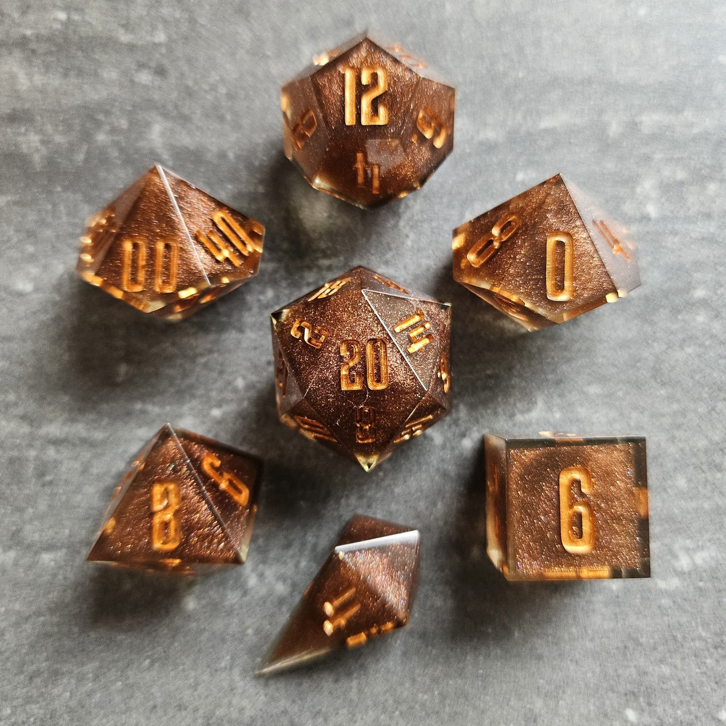 Set of bronze polyhedral dice on a gray surface