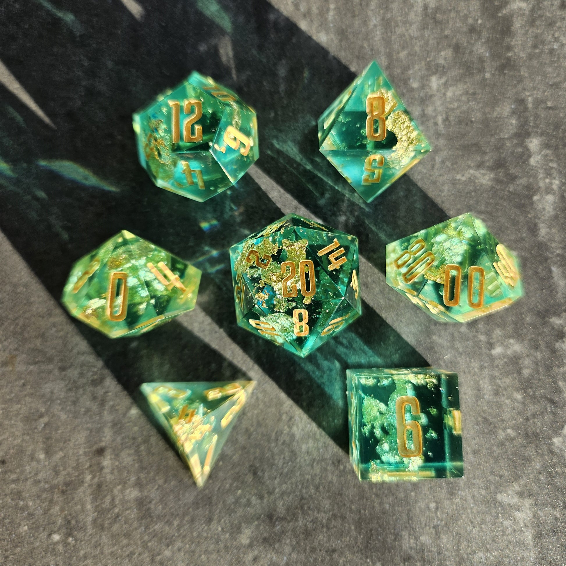 Set of green polyhedral dice with gold numbers on a dark surface
