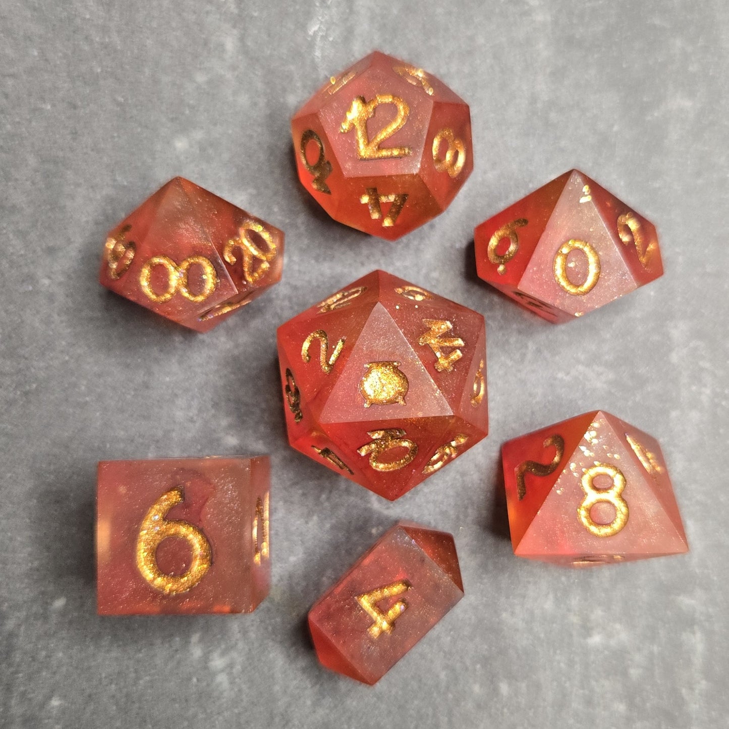 Set of red polyhedral dice with gold numbers on a gray surface